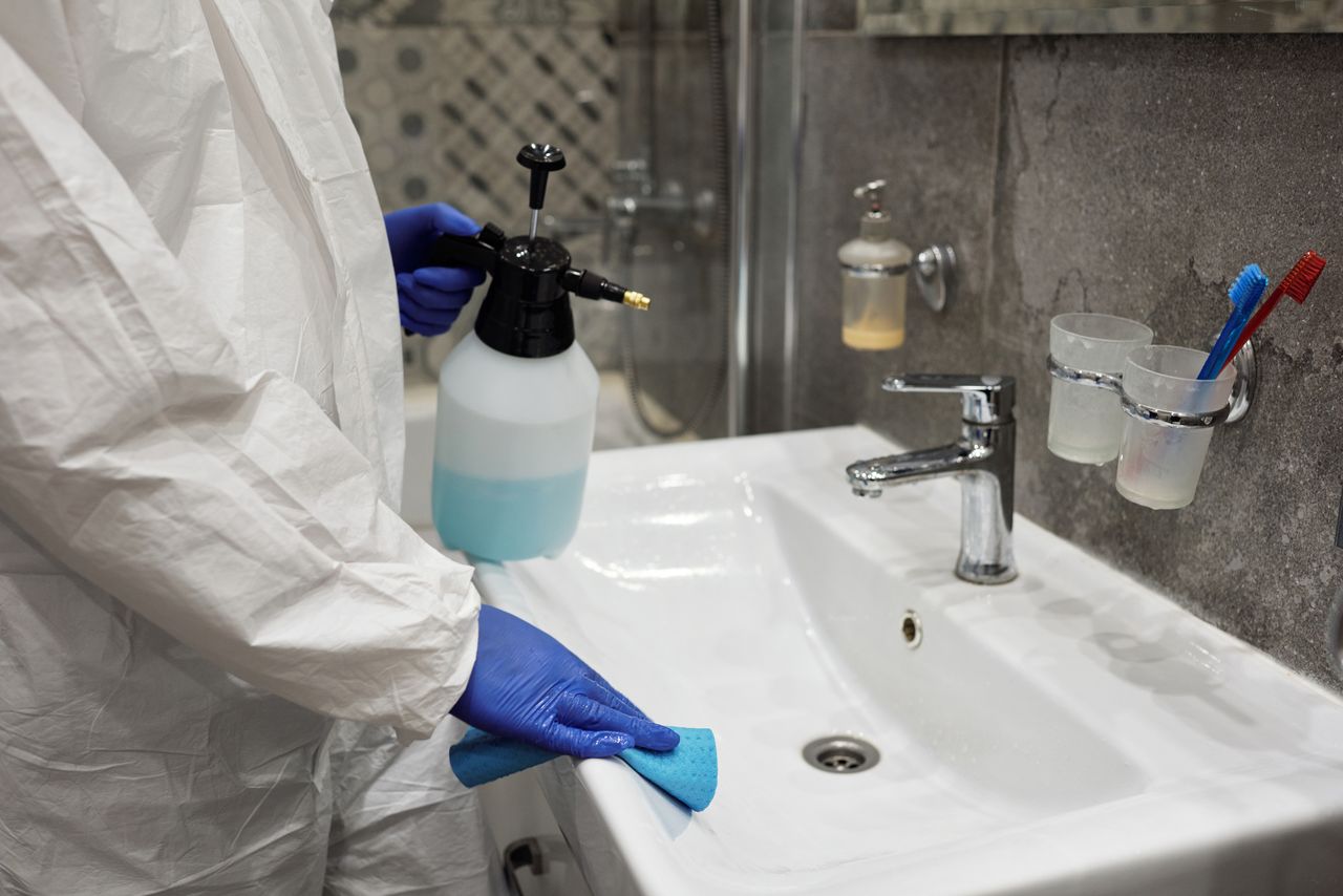 services-02 Une personne désinfecte un lavabo de salle de bain avec un vaporisateur, afin de garantir l'hygiène.